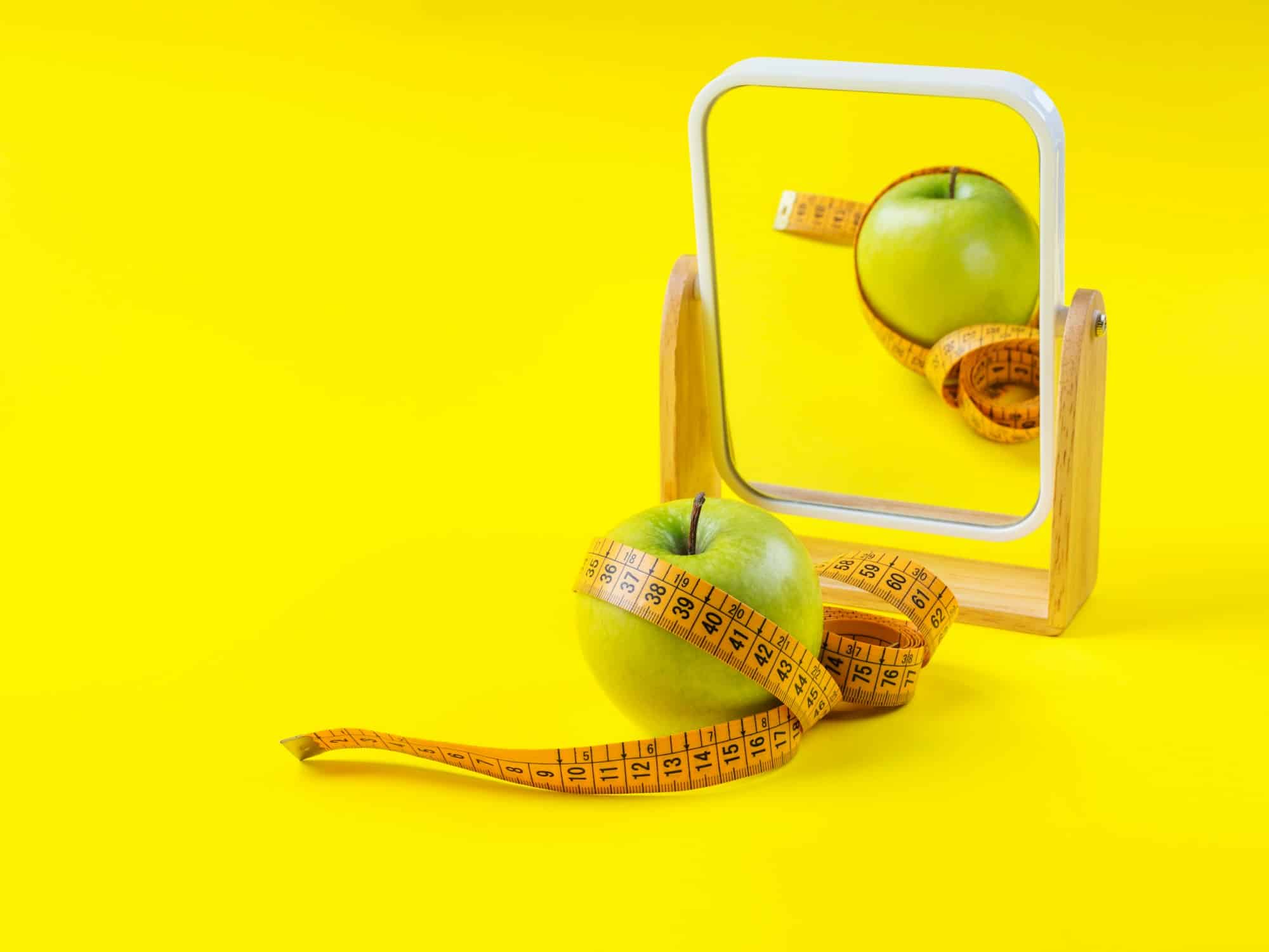 Apple with measuring tape reflected in the mirror