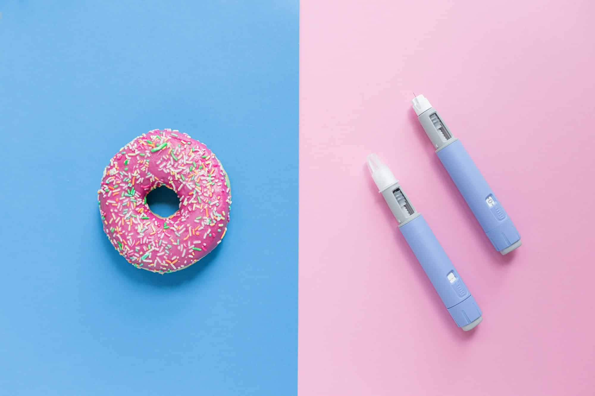 Delicious sweet pink donut on a blue background and two Ozempic pen injections