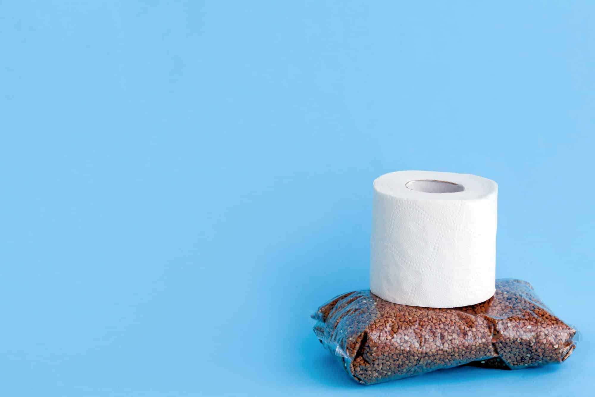 Buckwheat and toilet paper on blue background.