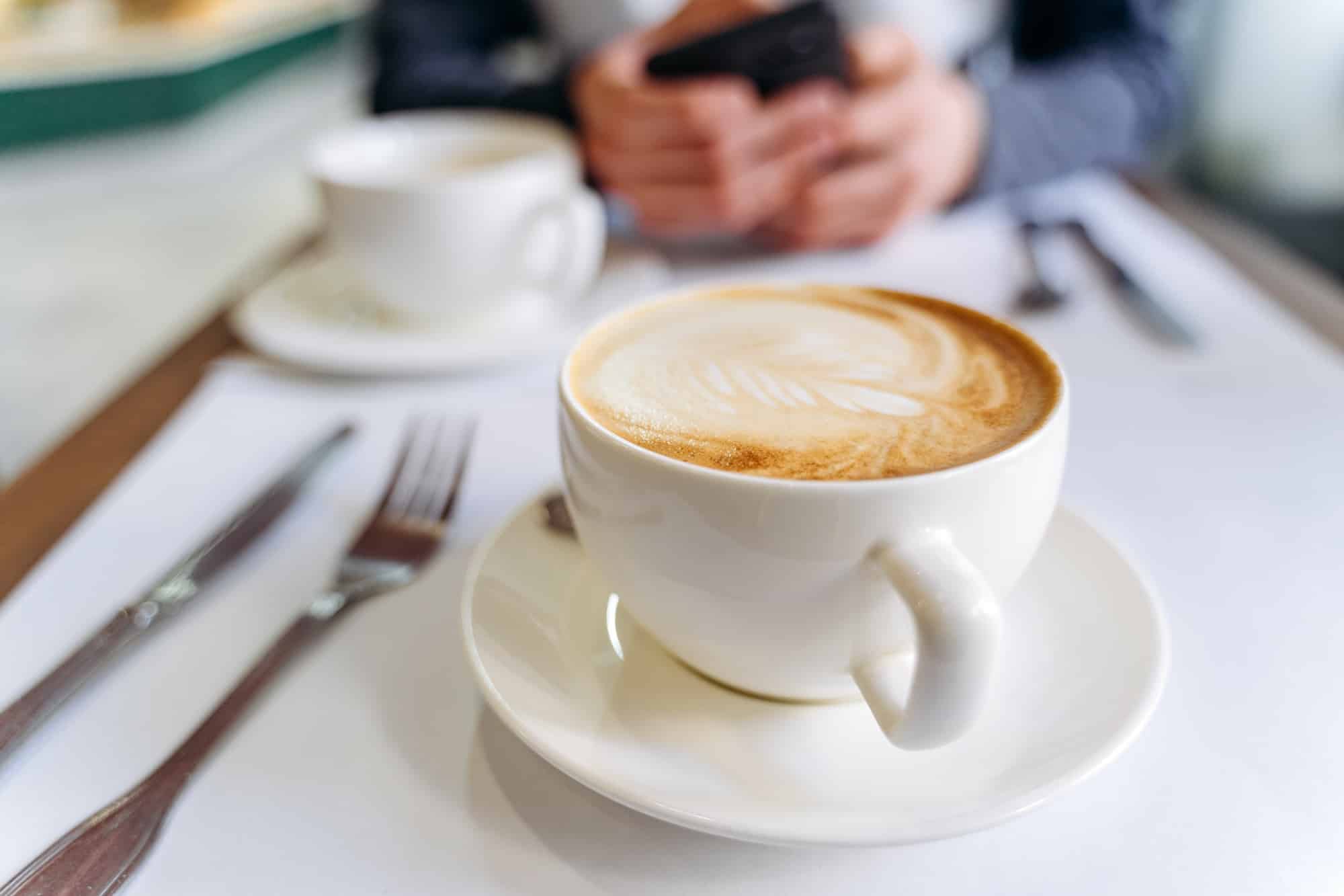 White cup of coffee on the table in a coffee shop.