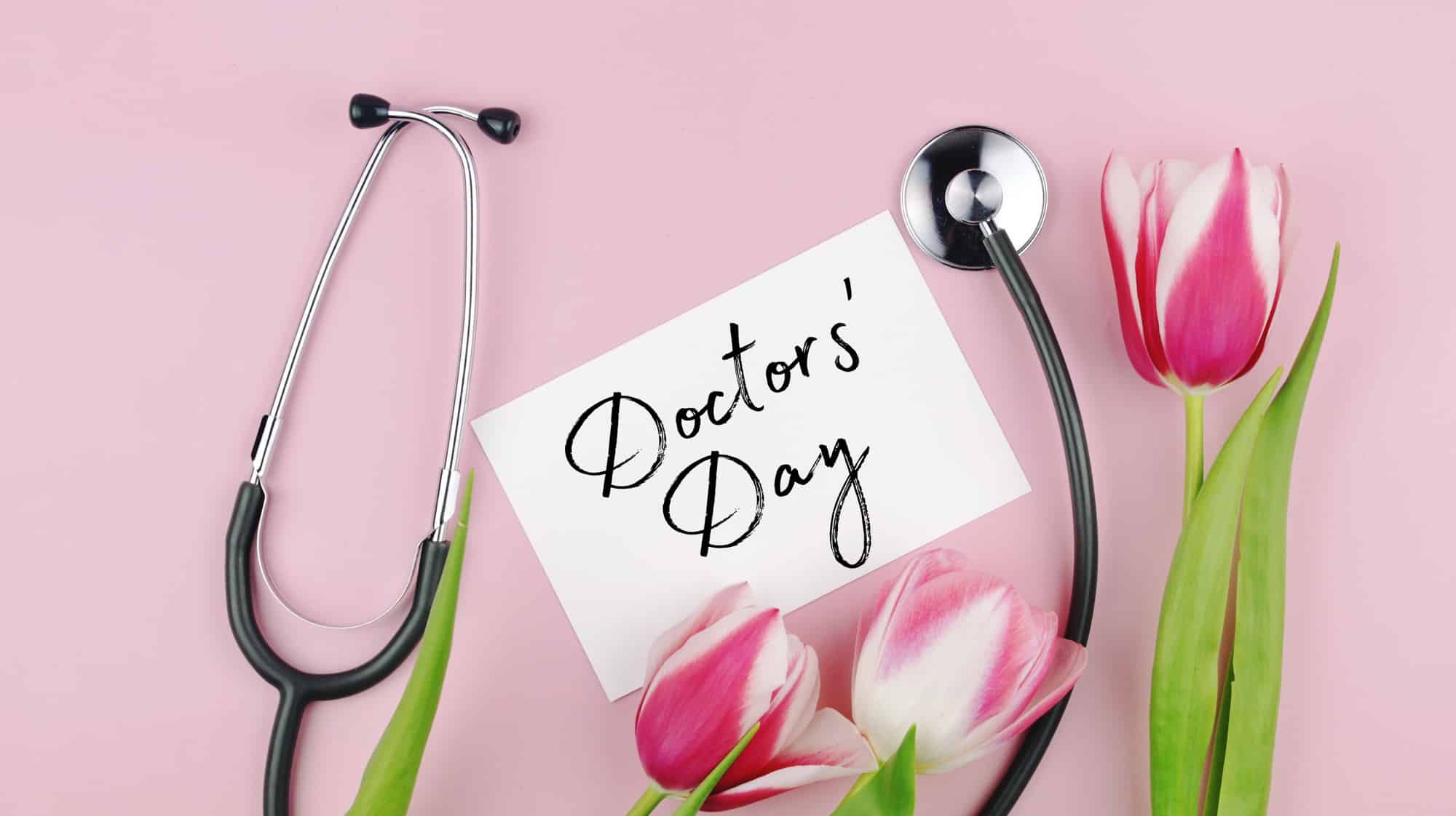 Tulips flowers and stethoscope with greeting card on a pink background. National Doctor’s day