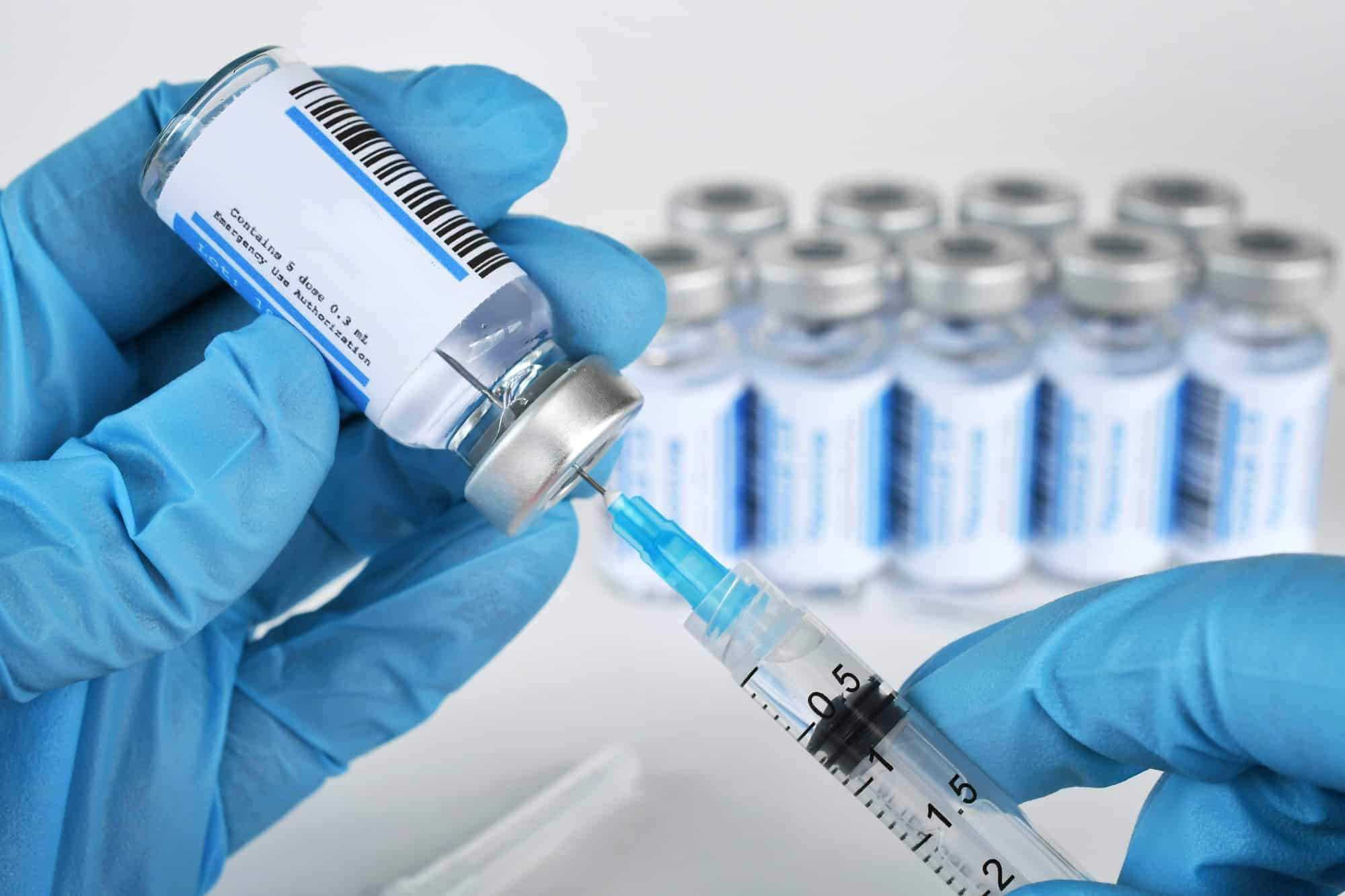 Medical personnel filling a syringe needle with generic vaccine booster from vial - mock up copy spa